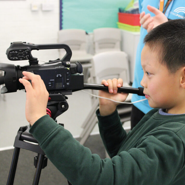 A schoolboy is filming with a video camera on a tripod